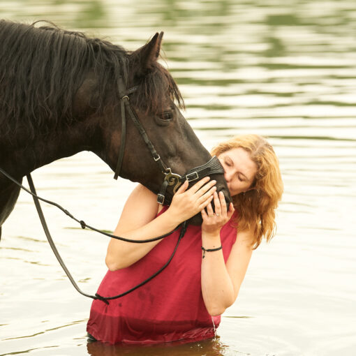 jeune femme embrassant son cheval dans l'eau valjoly